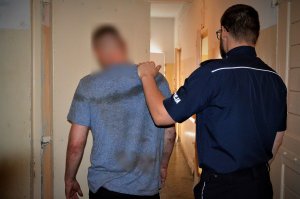policjant prowadzi zatrzymanego