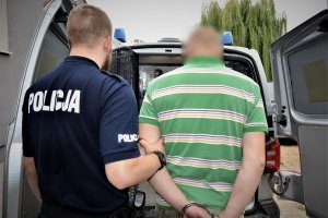 policjant doprowadza zatrzymanego
