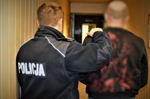 policjant doprowadza zatrzymanego