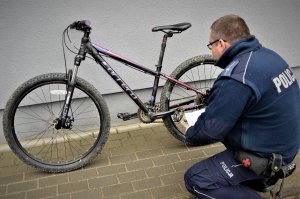 policjant wykonuje czynności przy rowerze
