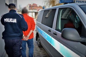 policjant doprowadza zatrzymanego