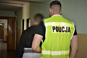 policjant doprowadza zatrzymanego