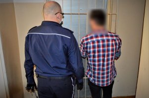 policjant doprowadza zatrzymanego