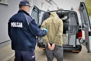 policjant doprowadza zatrzymanego