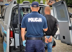 policjant doprowadza zatrzymanego