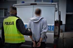 policjant doprowadza zatrzymanego