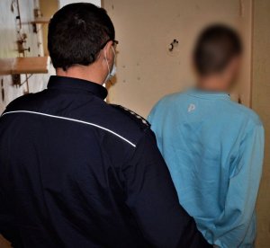 policjant doprowadza zatrzymanego