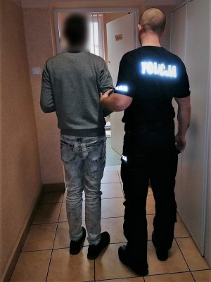 policjant doprowadza zatrzymanego