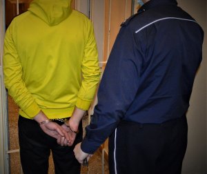 policjant doprowadza zatrzymanego