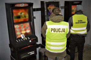 policjanci z funkcjonariuszami KAS zabezpieczają nielegalne maszyny