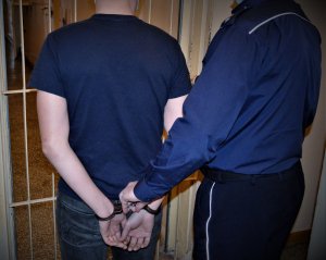 policjant doprowadza zatrzymanego