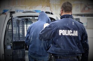 policjant doprowadza zatrzymanego