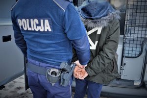 policjant doprowadza zatrzymanego