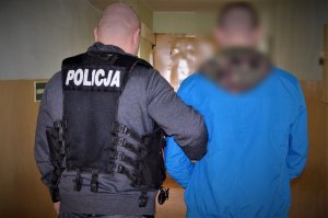 policjant doprowadza zatrzymanego
