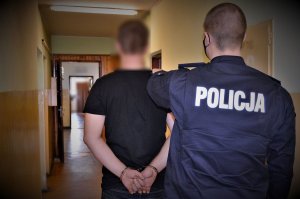 policjant doprowadza zatrzymanego