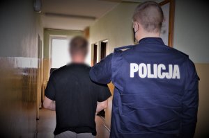policjant doprowadza zatrzymanego