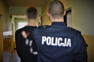 policjant doprowadza zatrzymanego