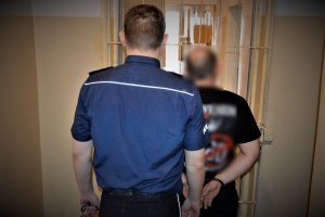 policjant doprowadza zatrzymanego