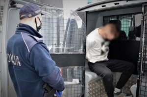 policjant doprowadza zatrzymanego