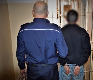 policjant wykonuje czynności z zatrzymanym