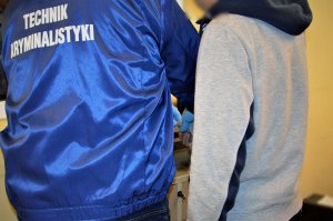 policjant wykonuje czynności z zatrzymanym