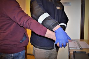 policjant wykonuje czynności z zatrzymanym