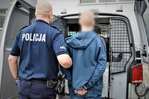 policjant doprowadza zatrzymanego