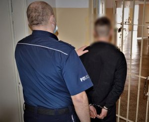 policjant doprowadza zatrzymanego