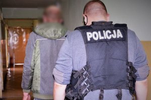 policjant doprowadza zatrzymanego