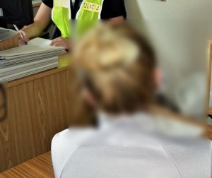 policjant przesłuchuje zatrzymaną kobietę