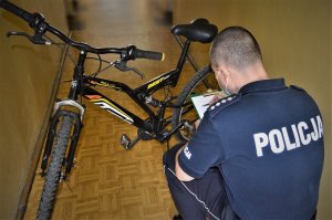 policjant przy zabezpieczonym rowerze