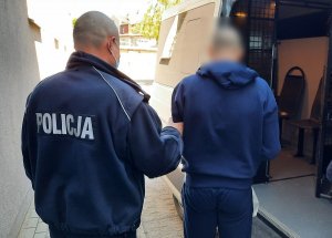 policjant doprowadza zatrzymanego