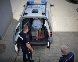policjanci doprowadzają zatrzymanego