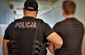 policjant doprowadza zatrzymanego