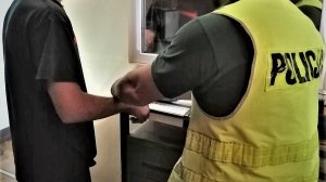 policjant wykonuje czynności z zatrzymanym