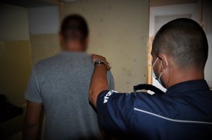 policjant doprowadza zatrzymanego