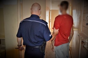 policjant doprowadza zatrzymanego
