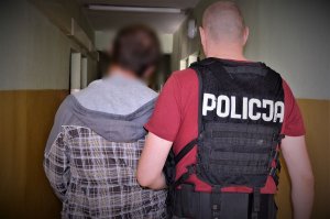 policjanci doprowadzają zatrzymanego