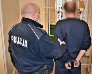 policjant doprowadza zatrzymanego