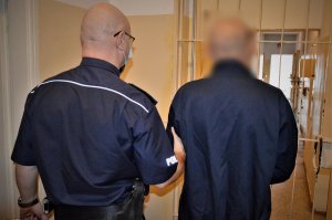 policjant doprowadza zatrzymanego