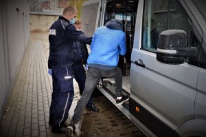 policjanci doprowadzają zatrzymanego