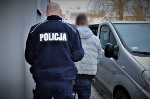 policjant doprowadza zatrzymanego