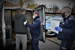 policjanci doprowadzają zatrzymanego