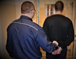 policjant doprowadza zatrzymanego