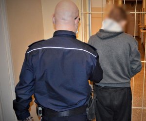 policjant doprowadza zatrzymanego