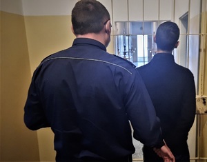 policjant doprowadza zatrzymanego