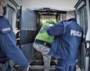 policjanci doprowadzają zatrzymanego