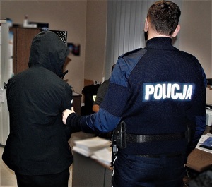 policjant doprowadza zatrzymanego