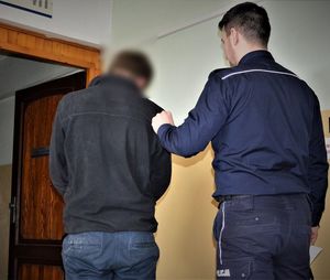 policjant doprowadza zatrzymanego