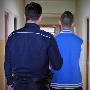 policjant doprowadza zatrzymanego